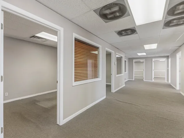 Spacious commercial corridor featuring neutral gray walls and patterned carpet flooring