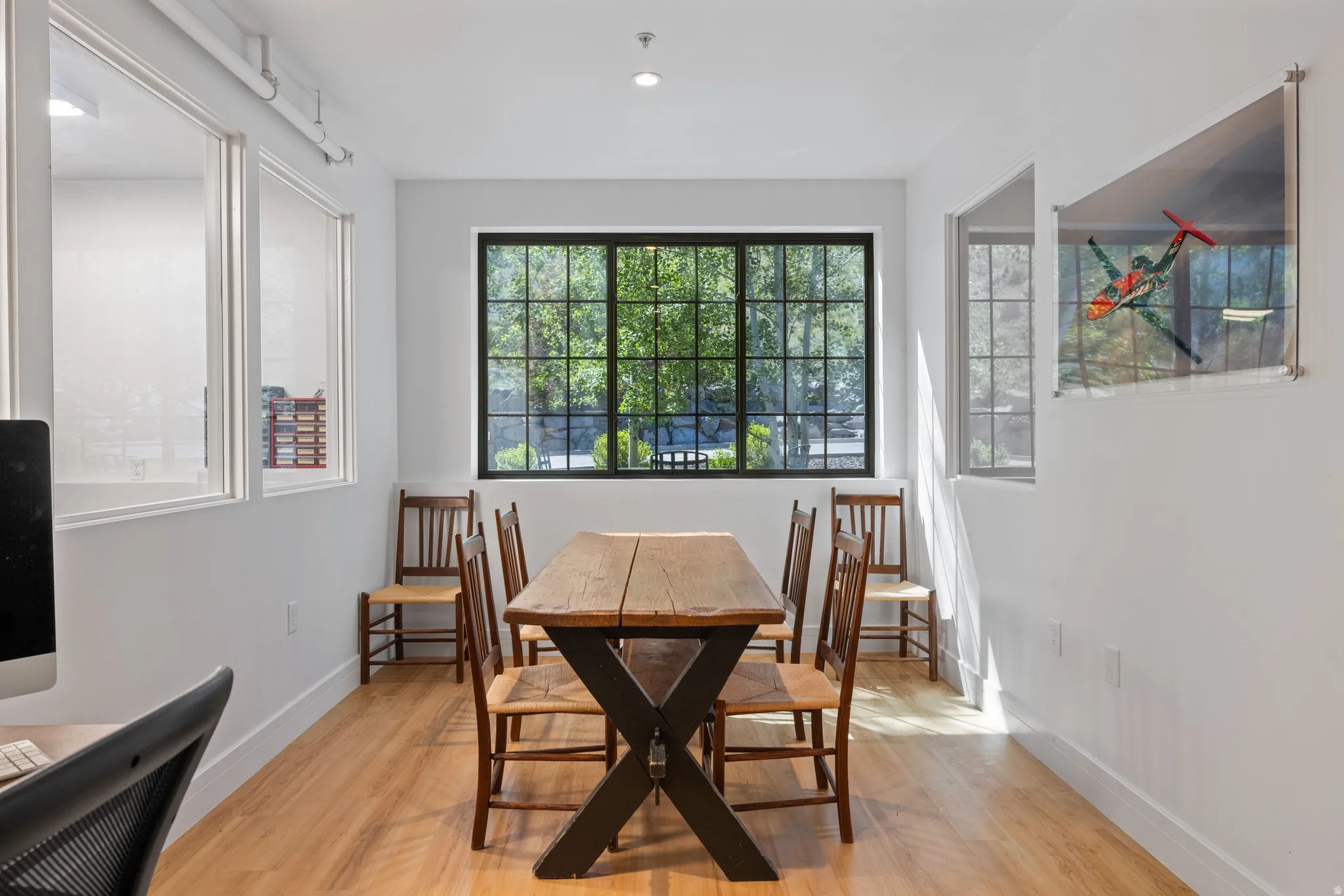 Bright room featuring a large gridded window, recessed lighting, light wood-finish flooring, and white walls