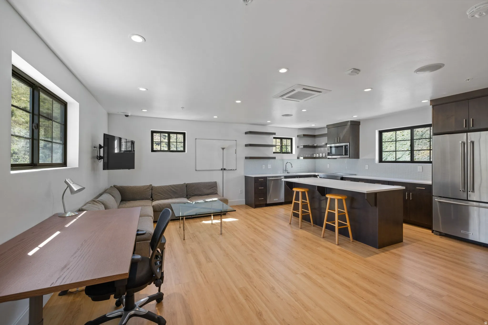 Open-concept living space featuring wood-finish flooring, recessed lighting, and multiple windows