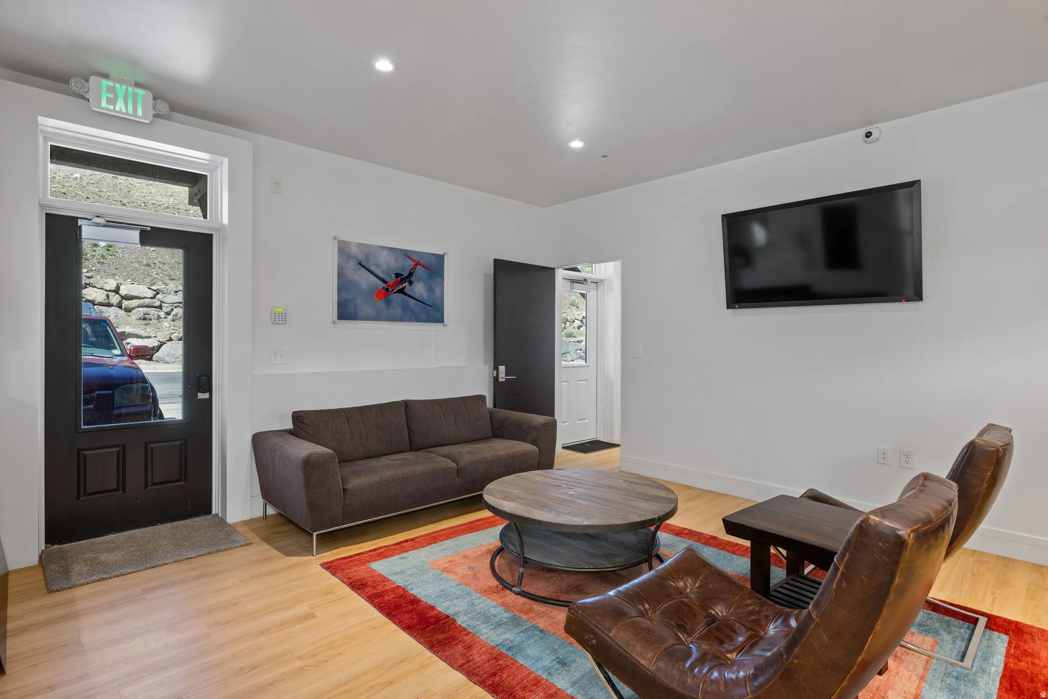 Lounge area with light wood-finish flooring, recessed lighting, and a wall-mounted flat-screen television