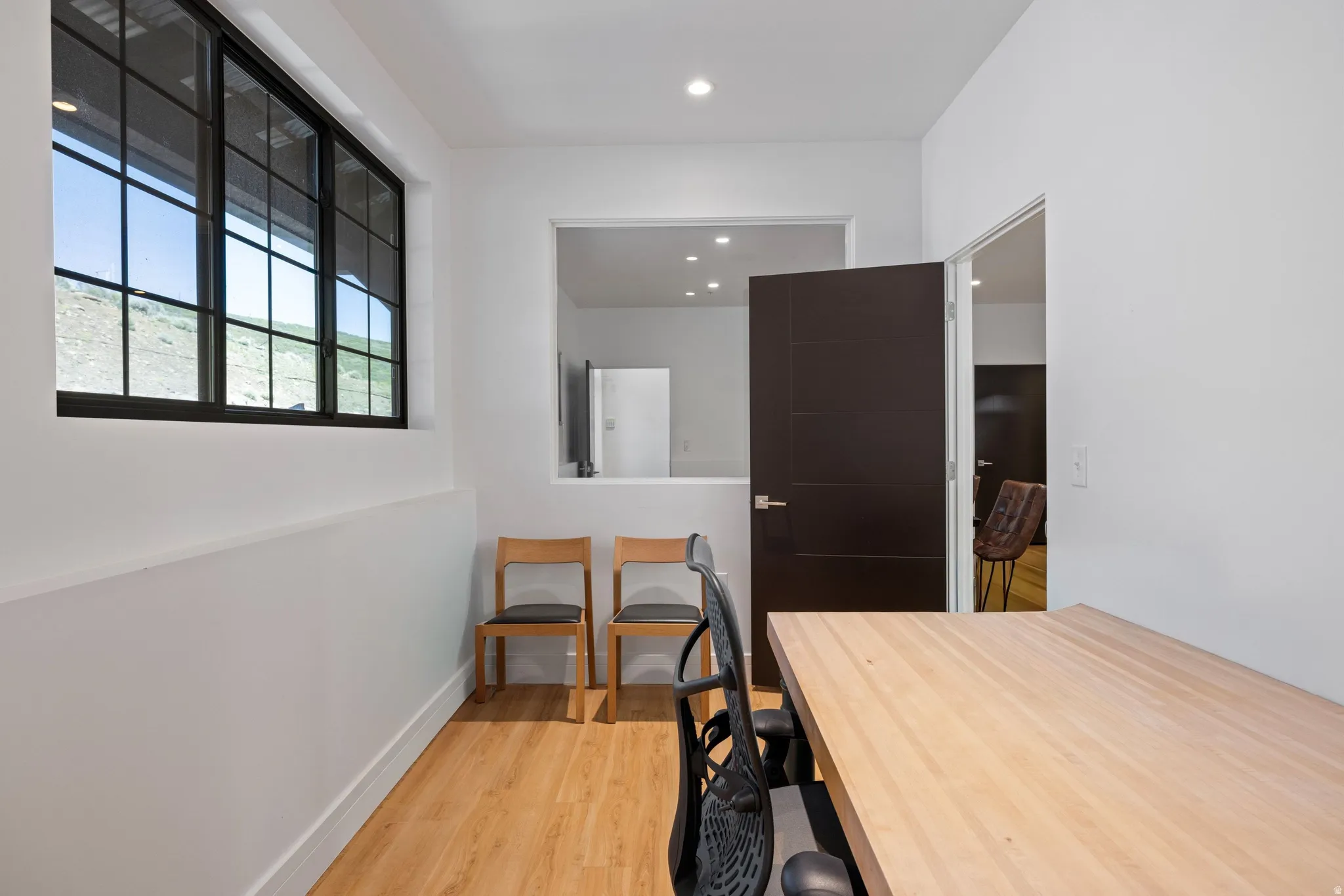 Room featuring wood-finish flooring, recessed lighting, and a large multi-pane window with black framing