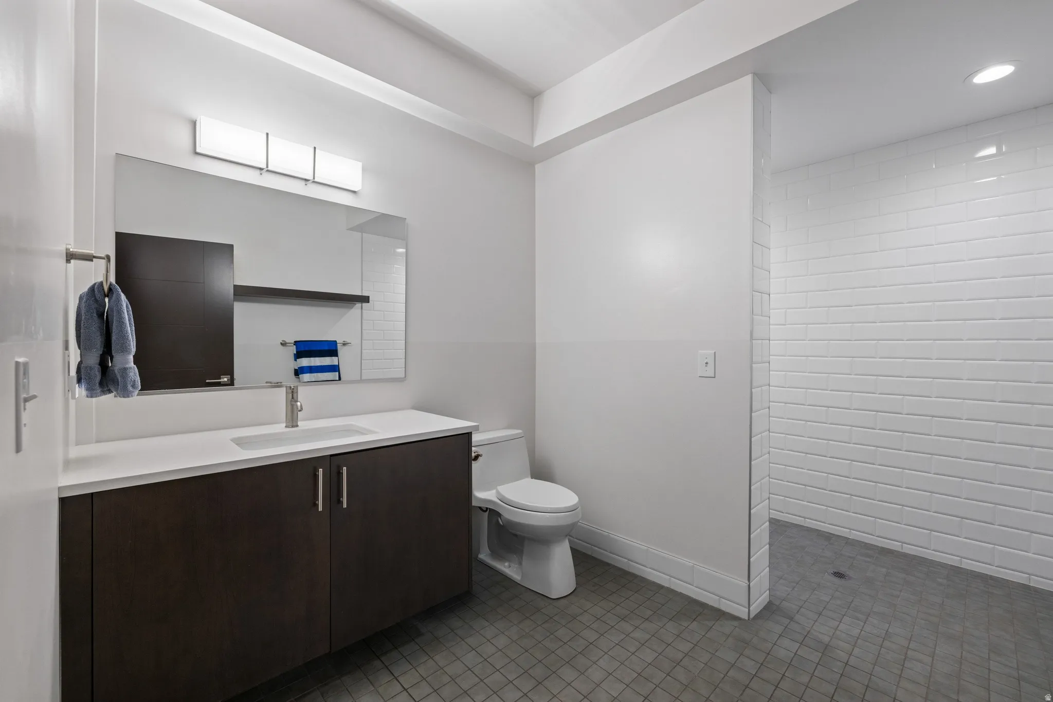 Bathroom featuring a dark wood-finish vanity with a white countertop, an undermount sink, and a rectangular mirror