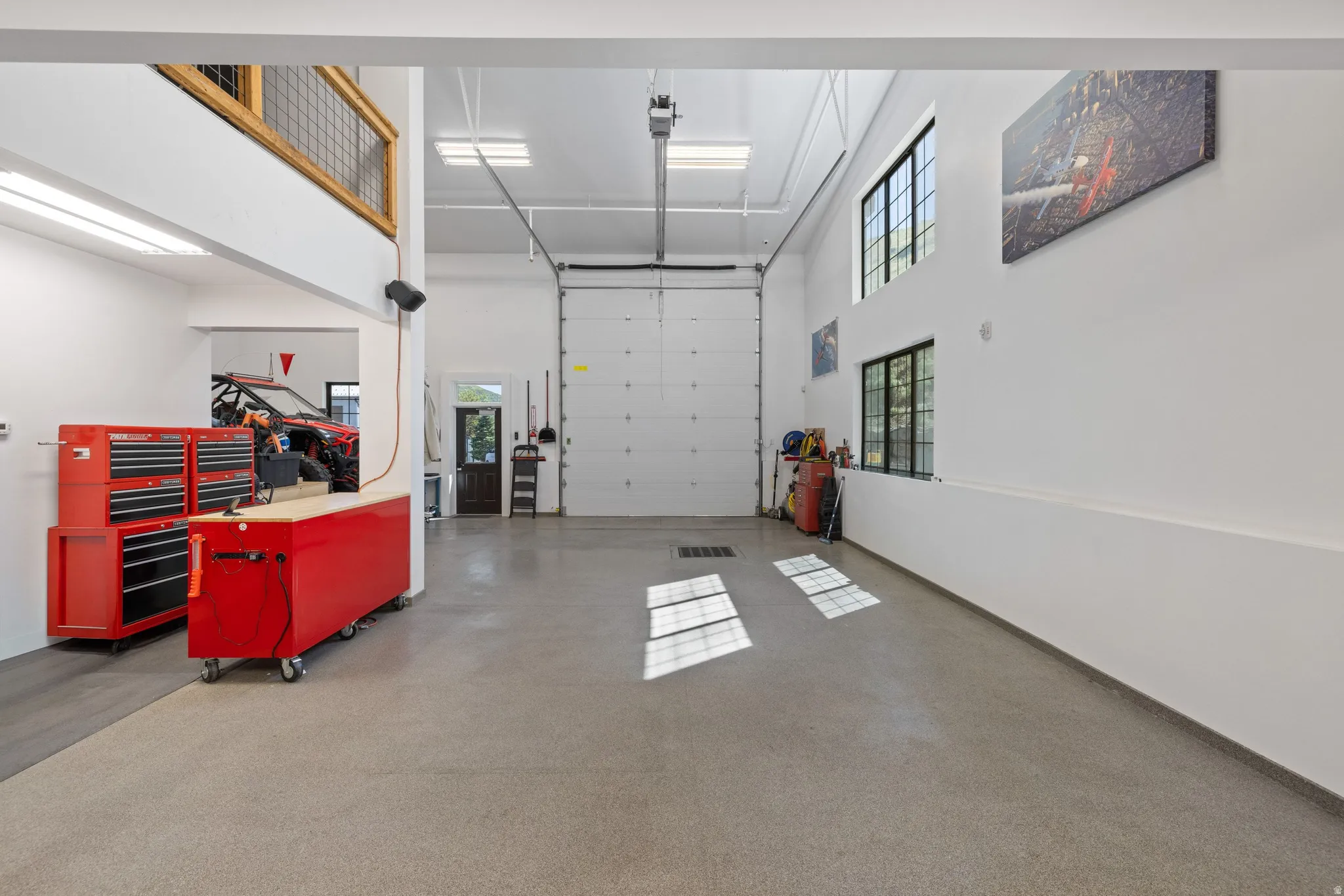 Expansive garage space featuring a large roll-up door, high ceilings with recessed lighting, and durable epoxy flooring