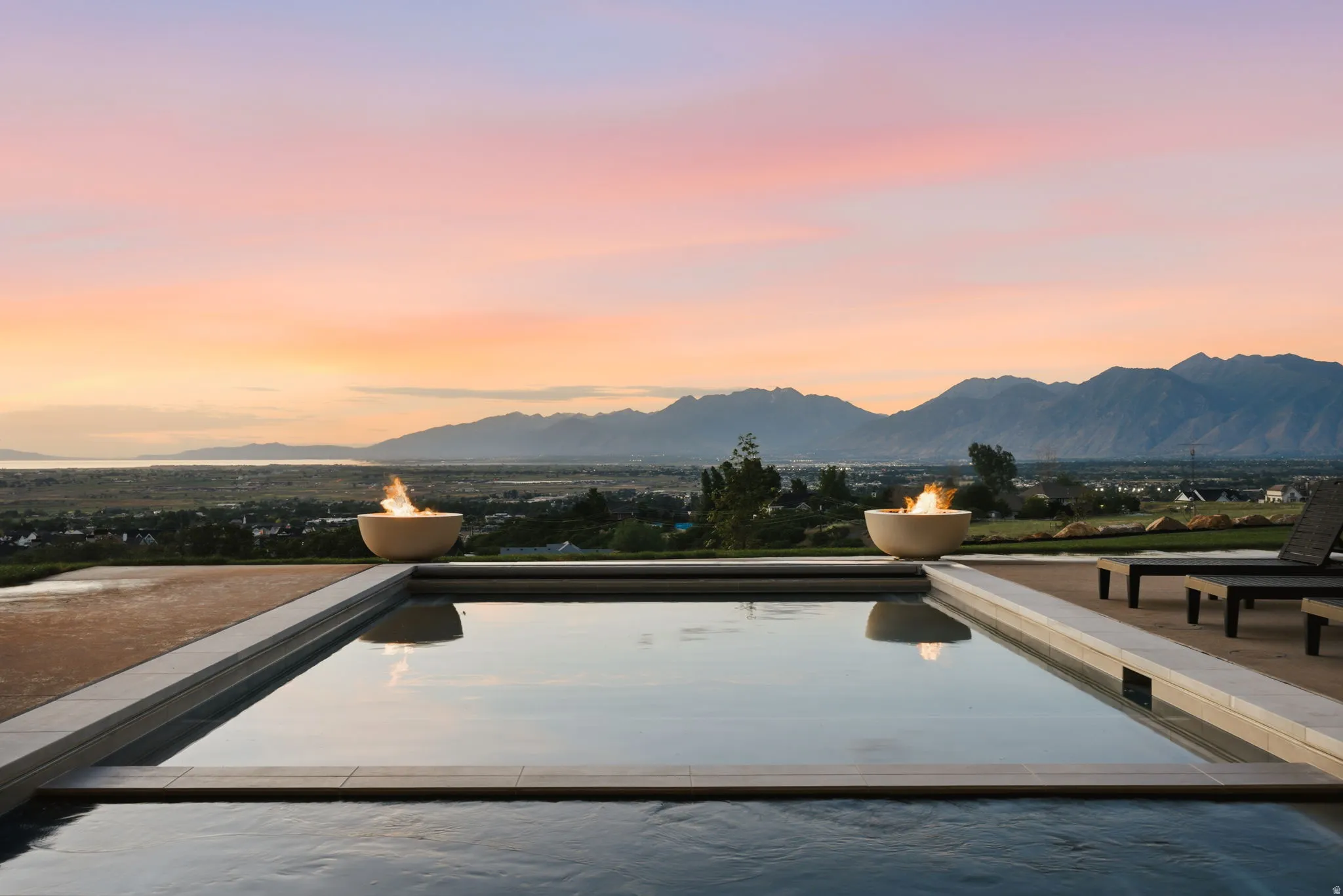 Outdoor pool area featuring a rectangular pool with integrated fire bowls