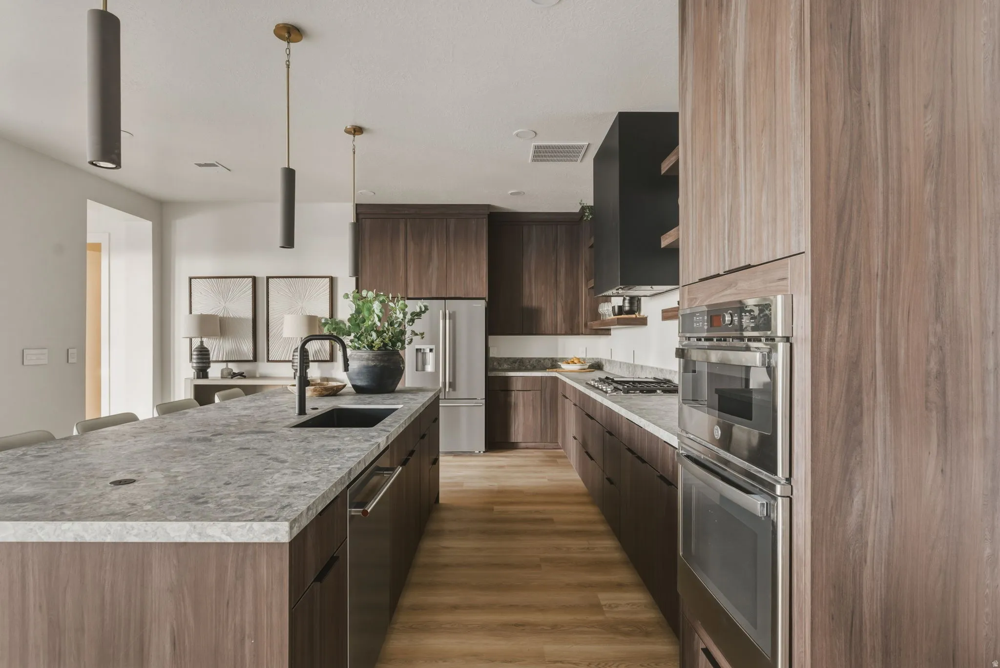 Contemporary kitchen featuring wood-finish cabinetry, light-toned stone countertops, and stainless steel appliances