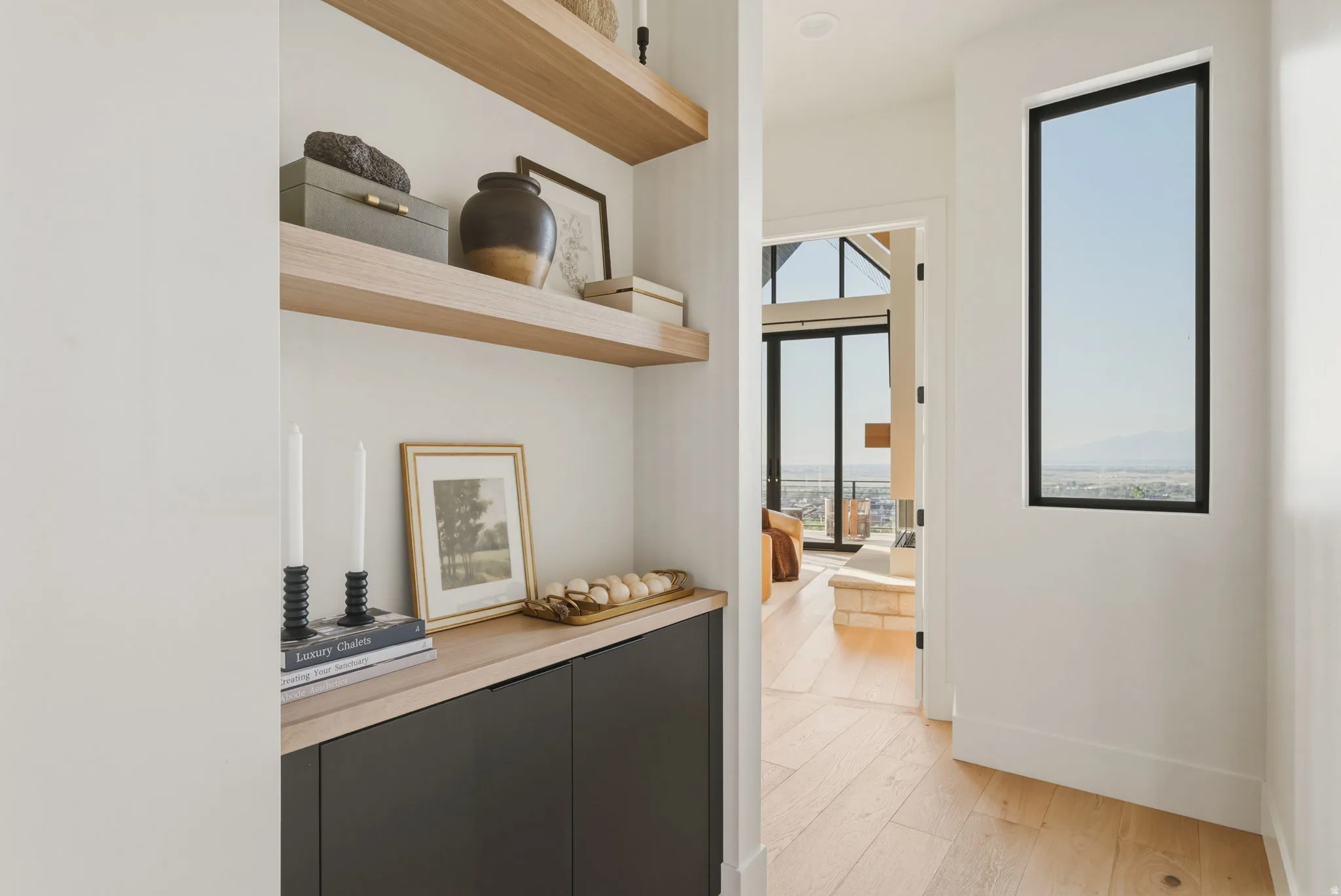 Open hallway with wood-finish flooring, a tall vertical window, and a built-in cabinet with floating shelves