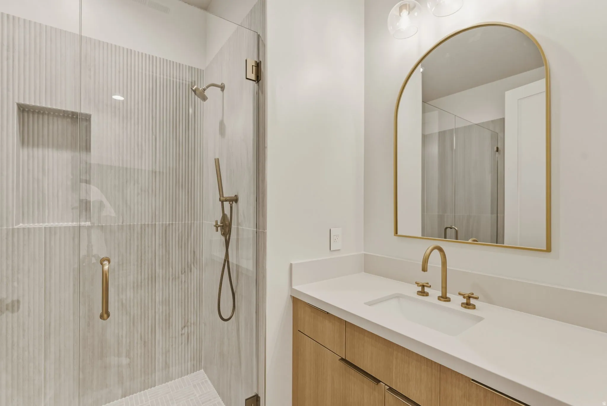Contemporary bathroom featuring a frameless glass shower enclosure with fluted tile walls and a built-in niche
