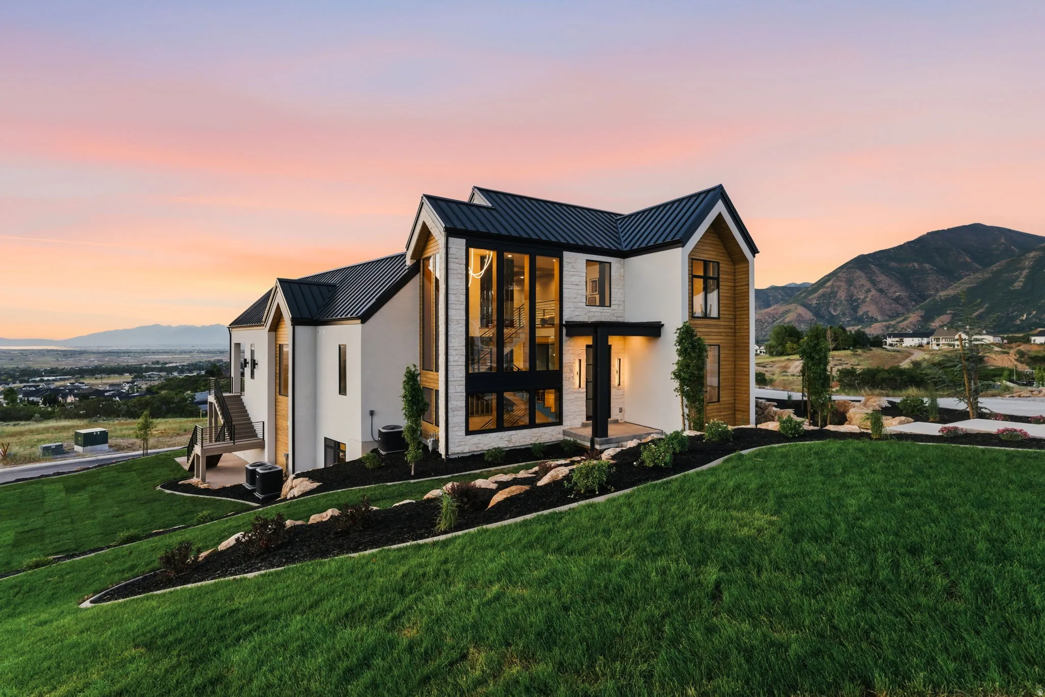 Contemporary architectural design featuring a prominent black metal roof, white stucco, and wood-finish siding accents