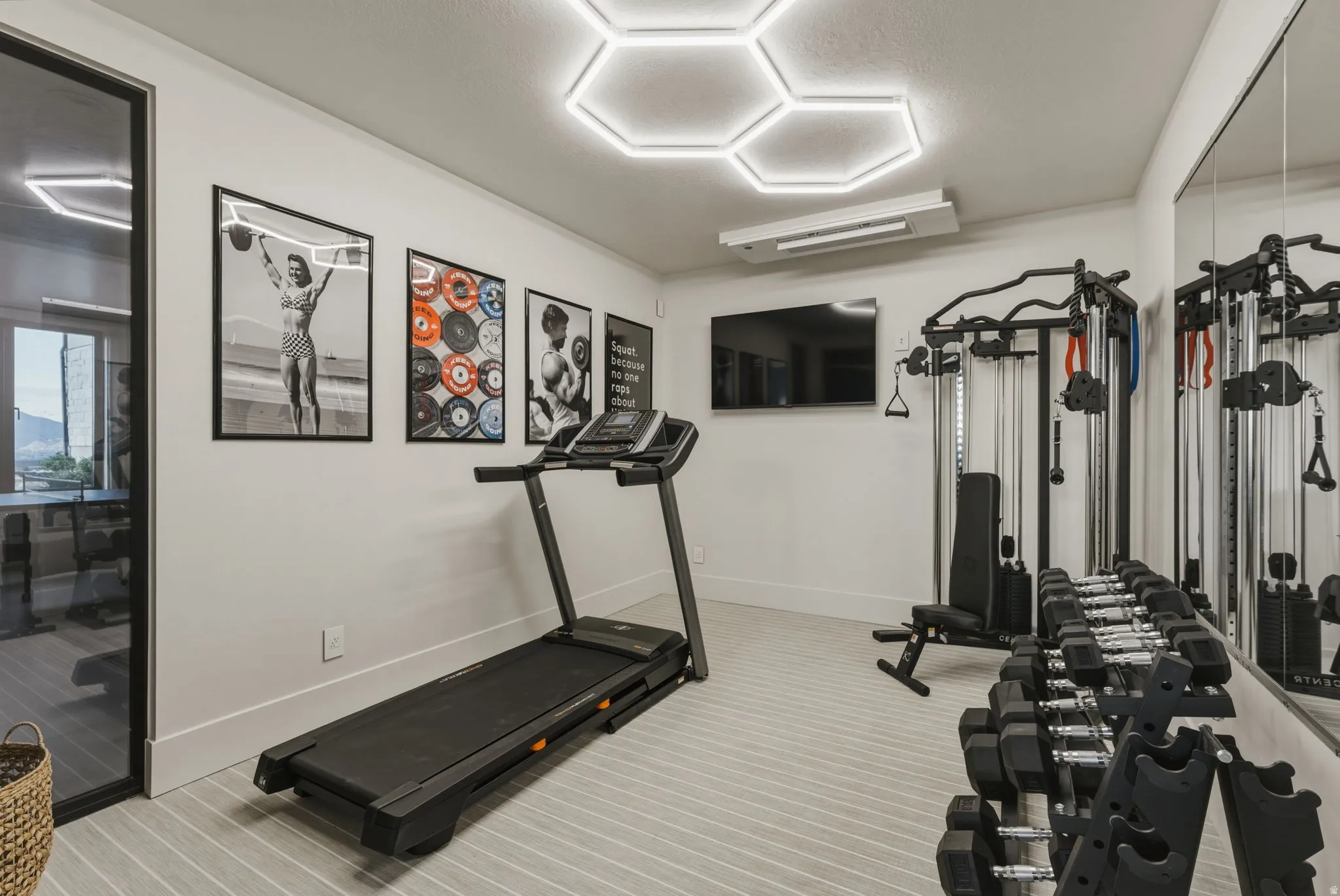 Dedicated fitness room featuring striped flooring, full-wall mirror, and hexagonal ceiling lighting