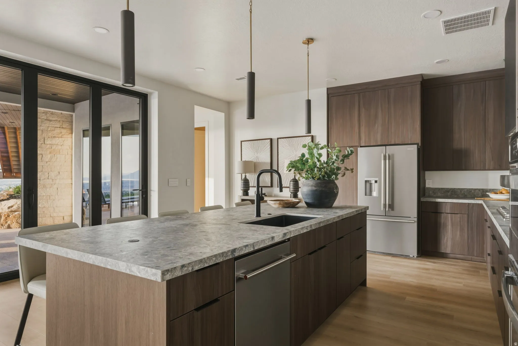 Kitchen island featuring a dark stone-finish countertop, undermount sink, and integrated dishwasher
