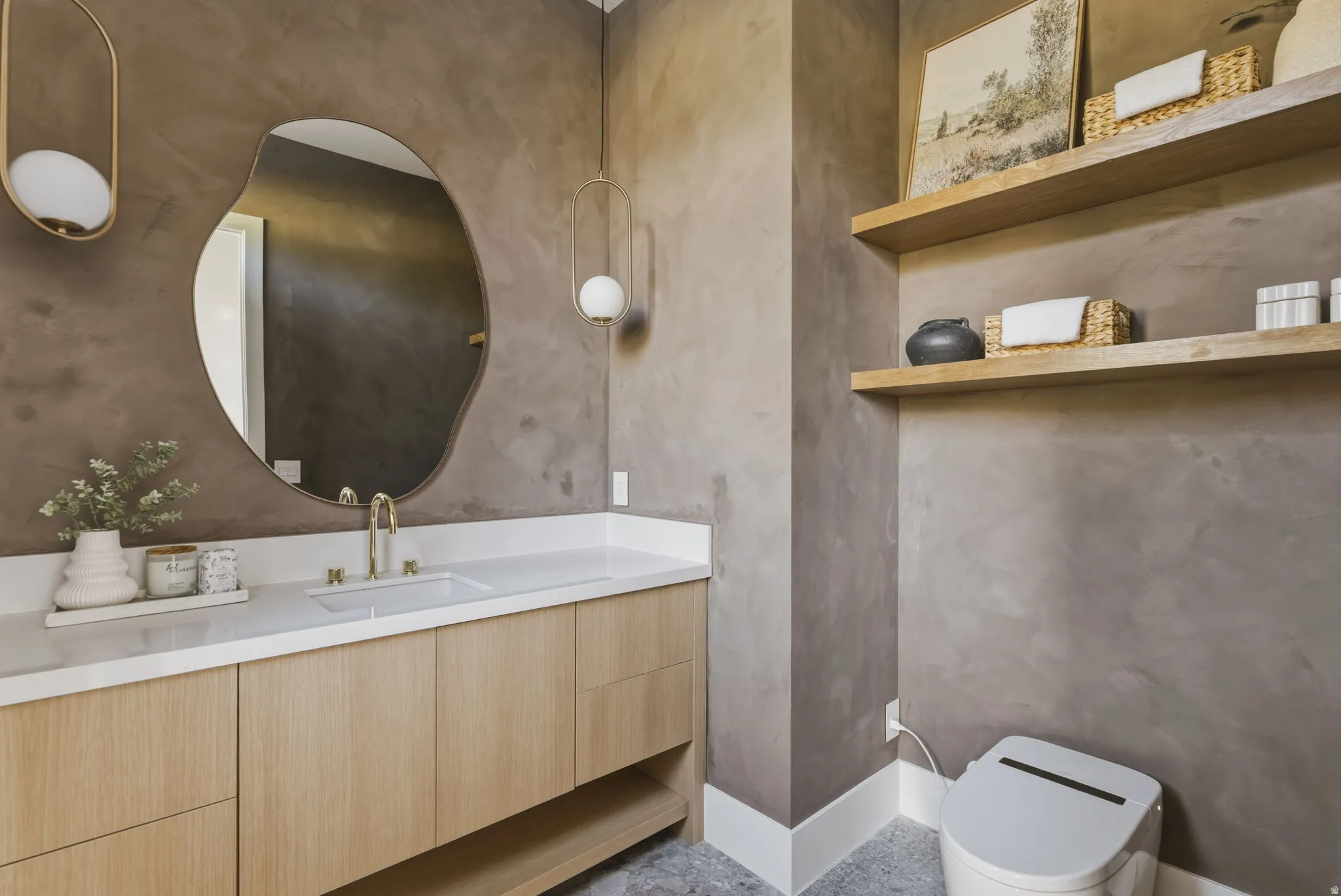 Vanity area featuring a light wood-finish cabinetry, a white countertop with an integrated sink, and a gold-tone faucet