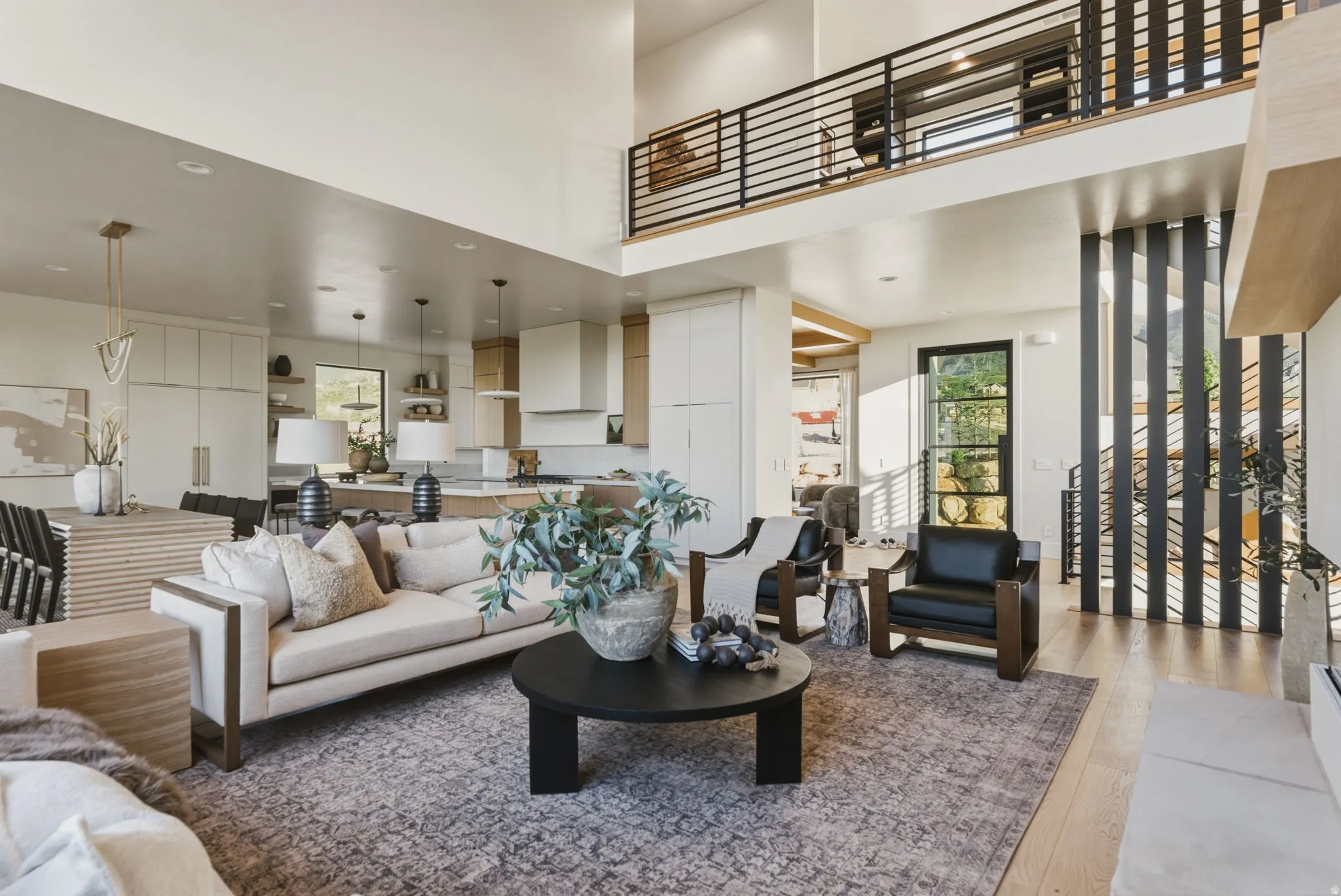 Open concept living space featuring a two-story ceiling, a contemporary black metal and wood-finish staircase, and light wood-finish flooring