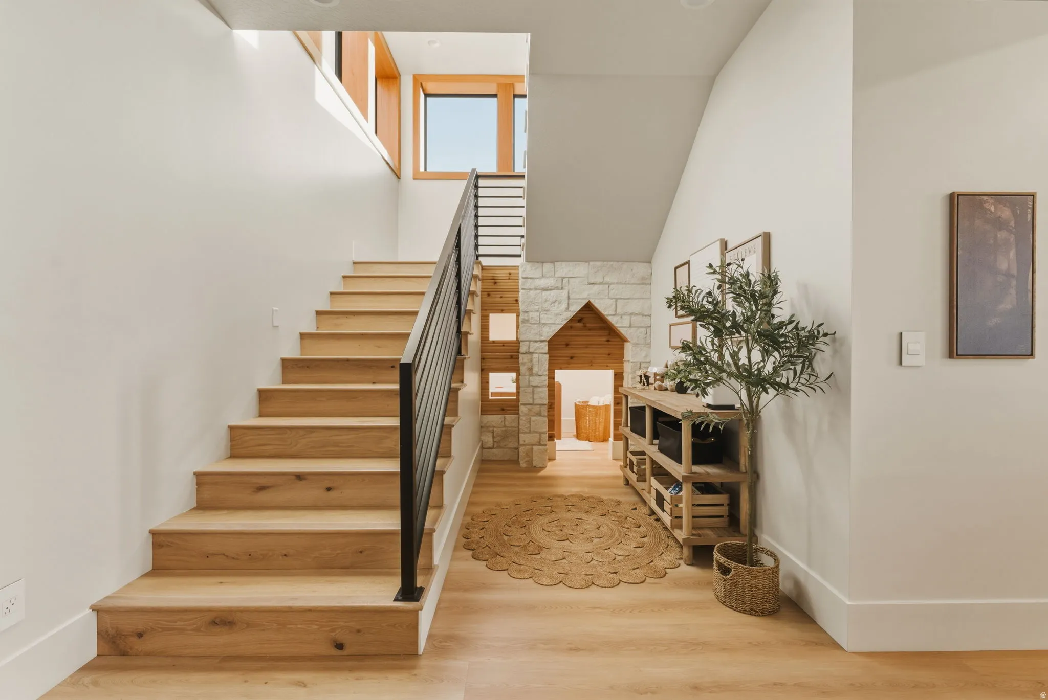 Staircase featuring wood-finish treads and risers, a matte black metal handrail, and white walls