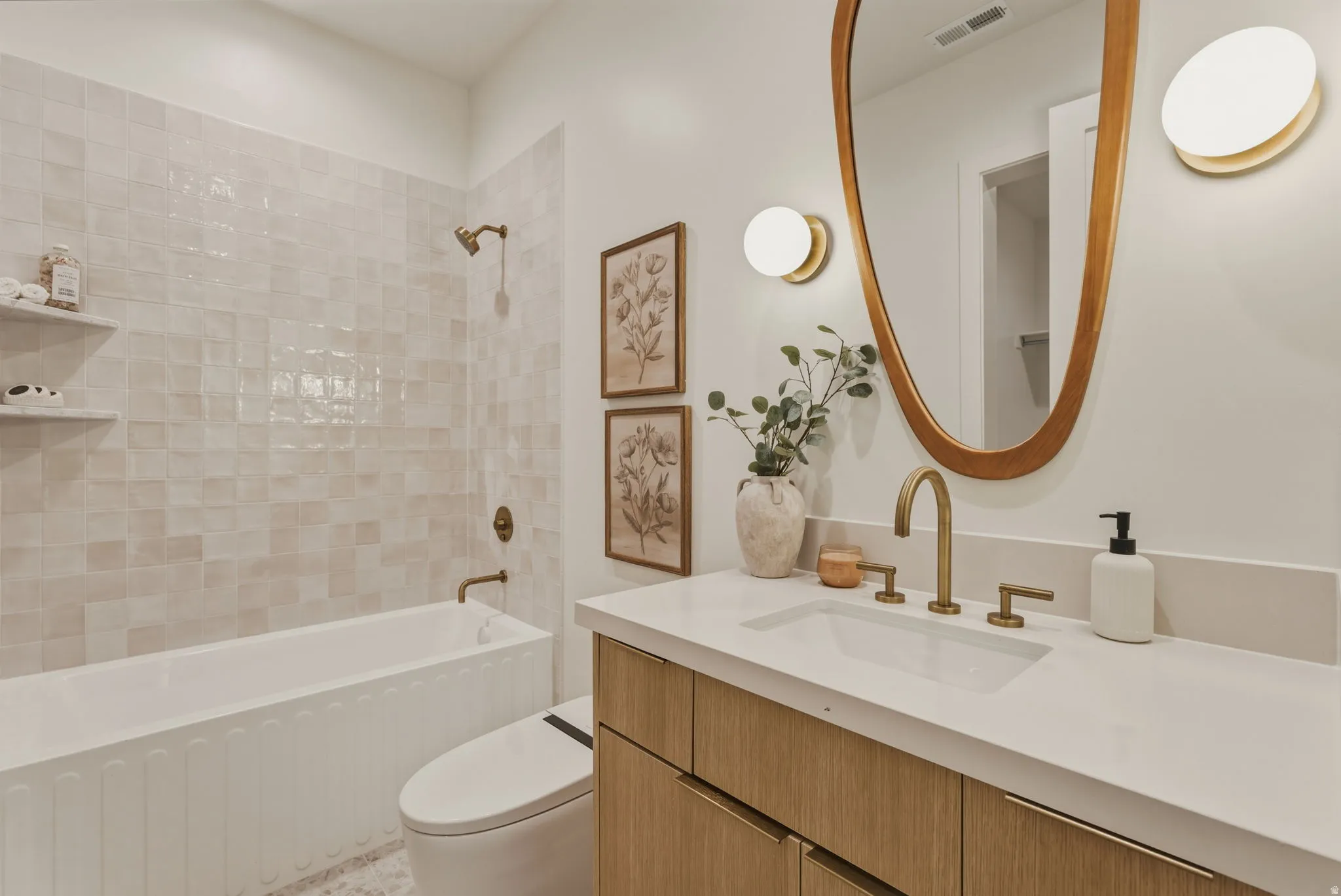 Bathroom featuring a vanity with wood-finish cabinetry, a white countertop, and a vessel sink with brass fixtures