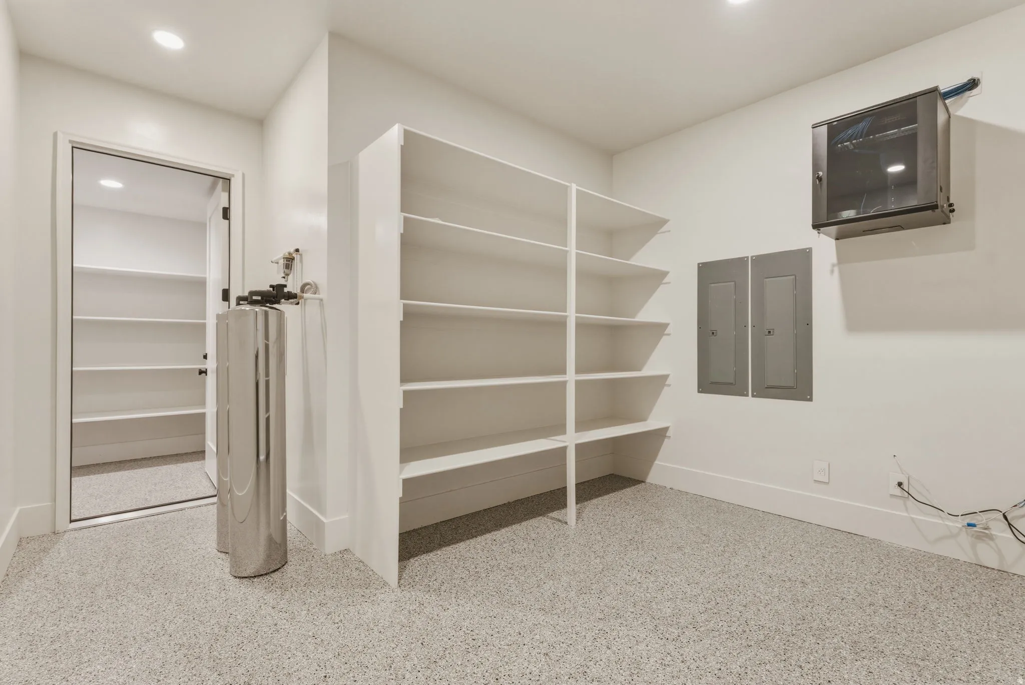 Utility room featuring epoxy flooring, built-in shelving, recessed lighting, and a water filtration system