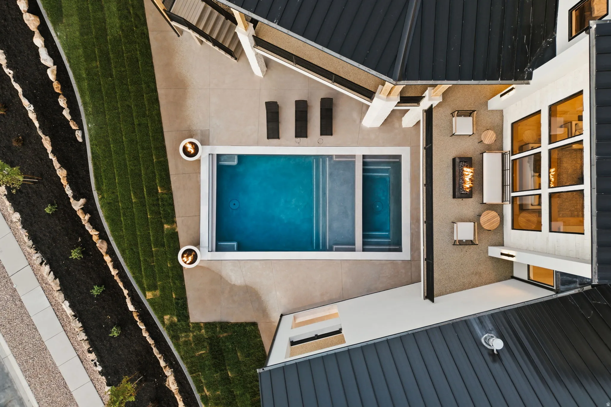 Outdoor living space featuring a rectangular swimming pool with integrated spa, adjacent patio with fire pit, and a multi-level deck