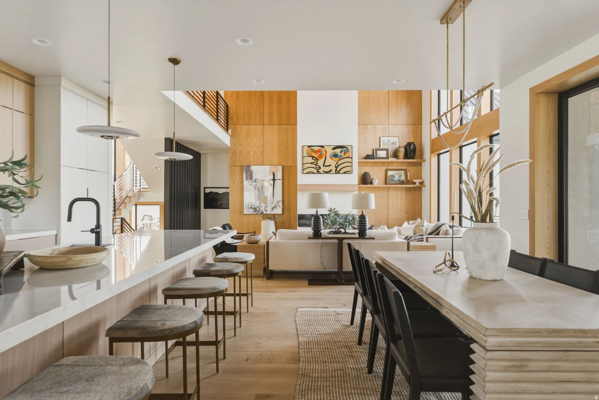 Expansive open-concept living space featuring wood-panel accent walls, high ceilings, and wood-finish flooring