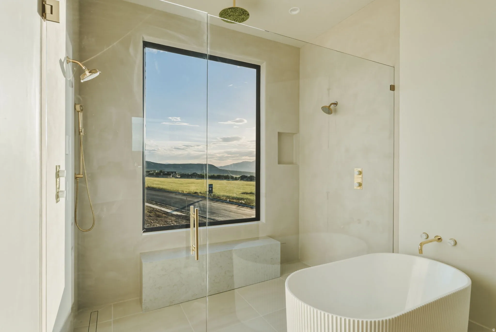 Contemporary bathroom featuring a spacious glass-enclosed shower with gold-tone fixtures, a freestanding soaking tub, a built-in shower bench, and a large picture window
