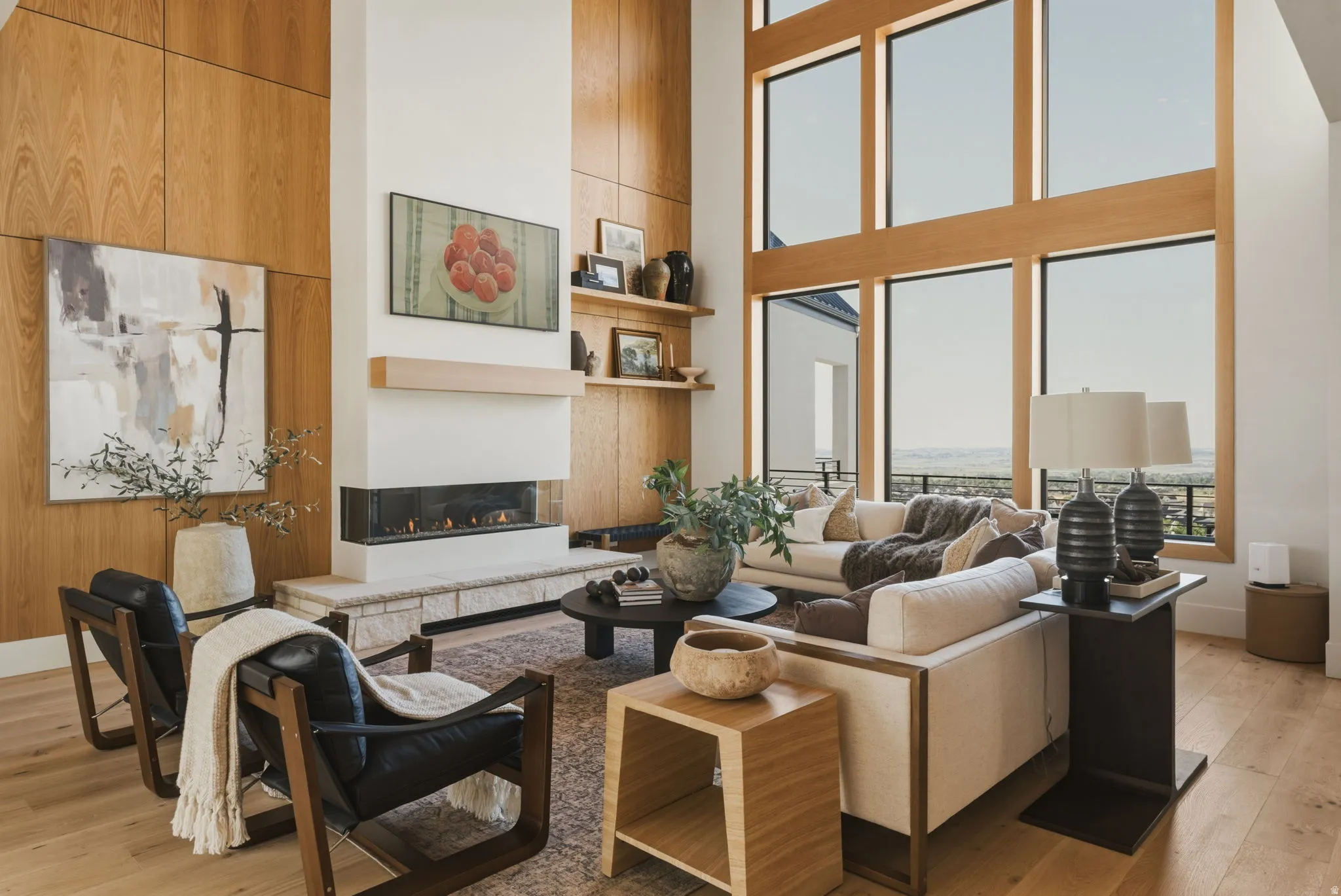 Great room featuring a contemporary linear fireplace with a stone hearth, wood-paneled accent wall, and expansive floor-to-ceiling windows with wood frames