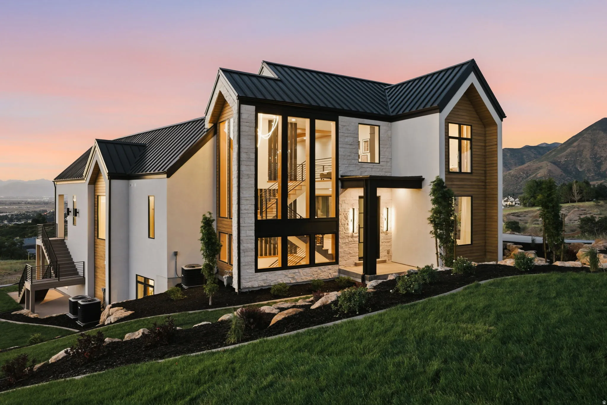 Modern architectural residence featuring a prominent gabled roofline, expansive floor-to-ceiling windows, and a multi-level exterior staircase