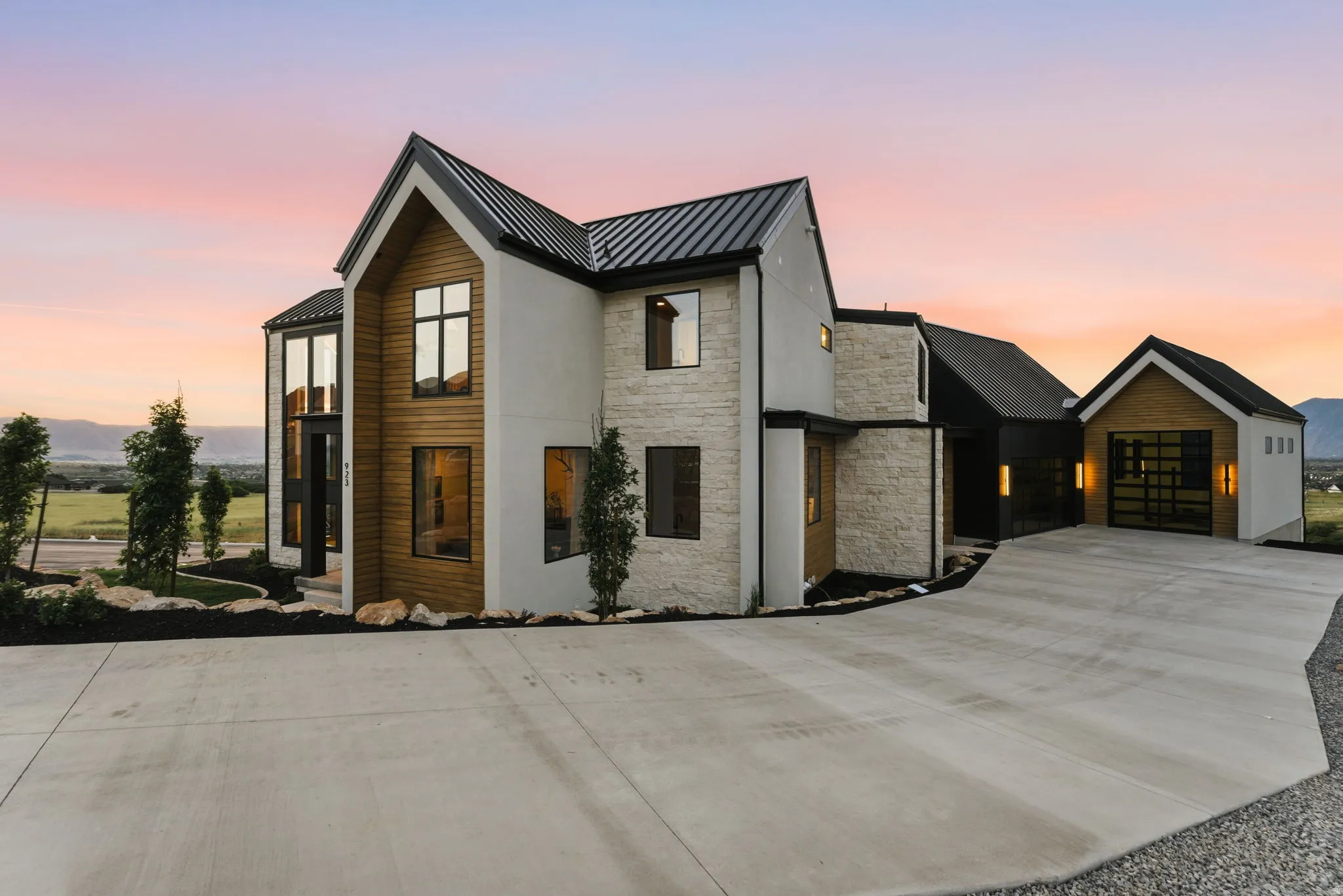 Modern architectural design featuring a prominent peaked roofline and a combination of white stucco, natural wood paneling, and stone veneer accents