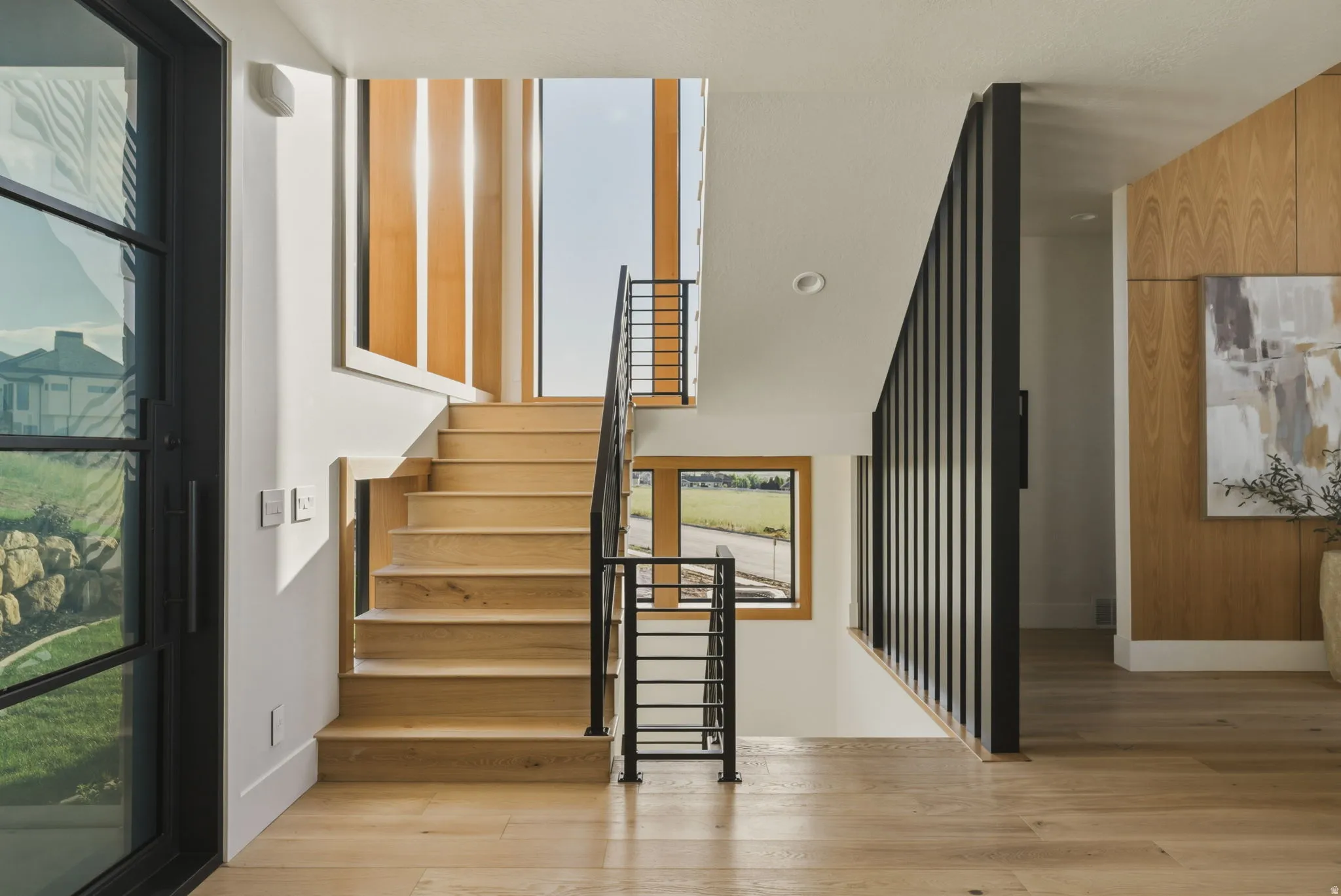 Light wood-finish staircase with black metal railings
