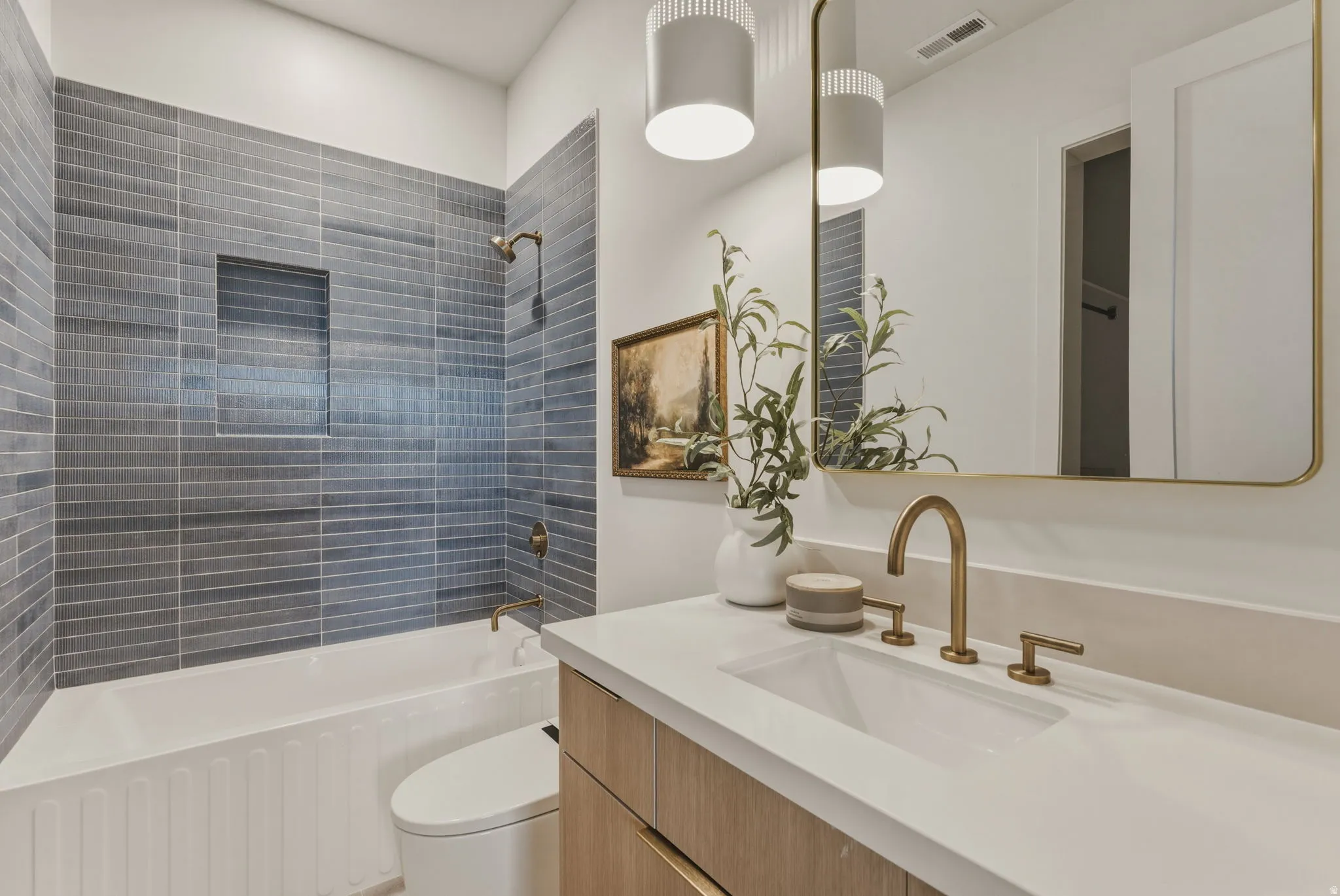 Bathroom featuring a white bathtub, gray horizontal tile surround with a built-in niche, and a gold-toned shower fixture