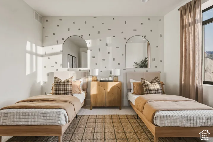 Bedroom featuring a patterned accent wall, two arched wall mirrors, and recessed ceiling lighting