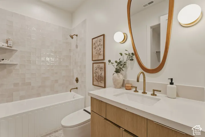 Bathroom featuring a vanity with wood-finish cabinetry, a white countertop, and a vessel sink with brass fixtures