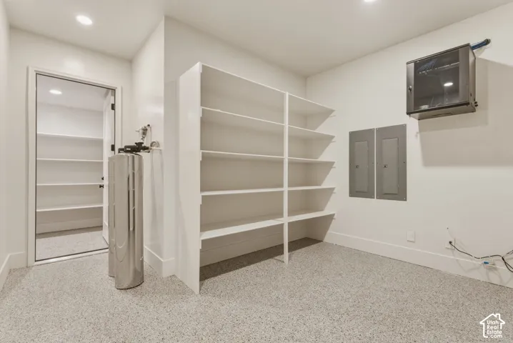 Utility room featuring epoxy flooring, built-in shelving, recessed lighting, and a water filtration system