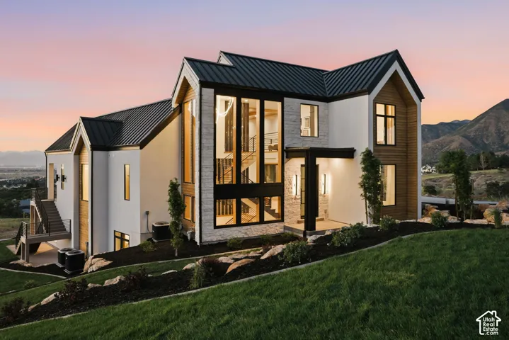 Modern architectural residence featuring a prominent gabled roofline, expansive floor-to-ceiling windows, and a multi-level exterior staircase