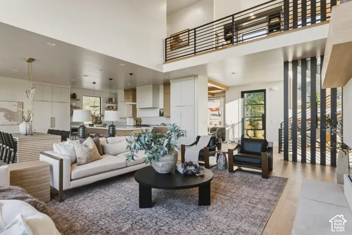 Open concept living space featuring a two-story ceiling, a contemporary black metal and wood-finish staircase, and light wood-finish flooring