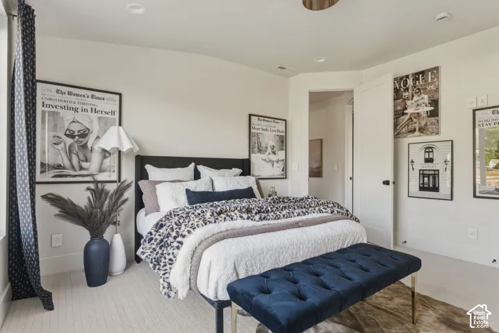 Bright sleeping area featuring recessed lighting, light-toned carpeting, a paneled door with dark hardware, a window with patterned drapes, and white walls