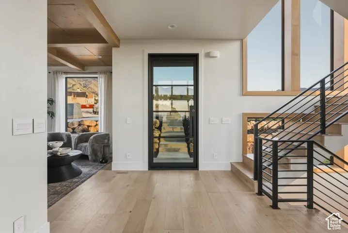 Entryway featuring a black-framed glass door, light wood-finish flooring, and a modern staircase with black metal railings