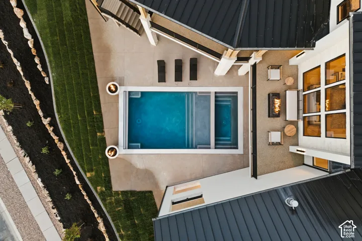 Outdoor living space featuring a rectangular swimming pool with integrated spa, adjacent patio with fire pit, and a multi-level deck