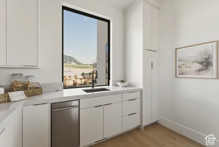 Kitchenette featuring a large picture window, undermount sink with a matte black faucet, and stone countertops