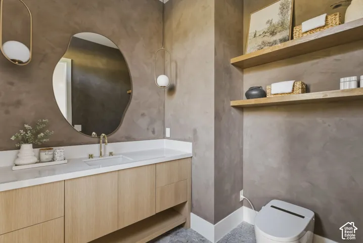 Vanity area featuring a light wood-finish cabinetry, a white countertop with an integrated sink, and a gold-tone faucet