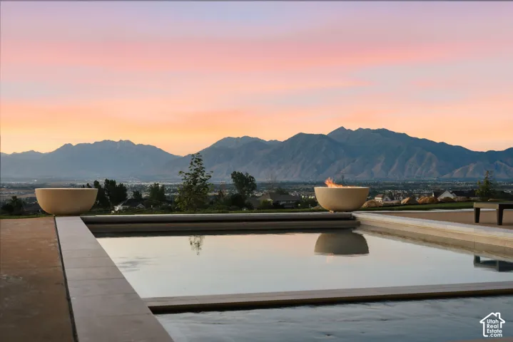 Outdoor pool with surrounding hardscape, two decorative fire bowls, and a mountain backdrop