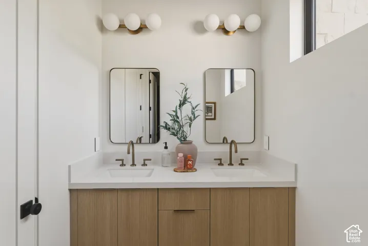 Dual vanity with wood-finish cabinetry, white countertops, and matte gold-tone fixtures
