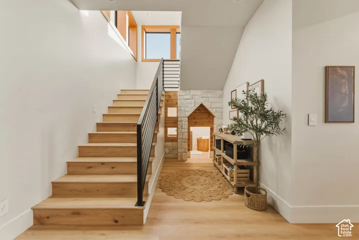 Staircase featuring wood-finish treads and risers, a matte black metal handrail, and white walls