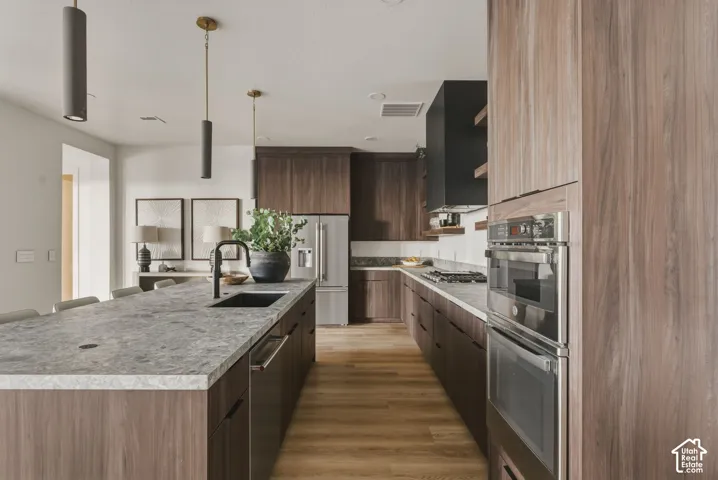 Contemporary kitchen featuring wood-finish cabinetry, light-toned stone countertops, and stainless steel appliances
