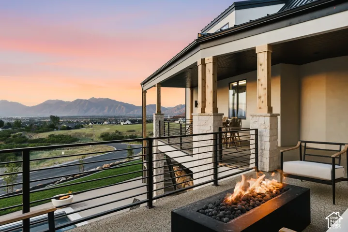Expansive outdoor patio featuring a built-in fire pit with lava rocks, durable stone tile flooring, and a contemporary black metal railing
