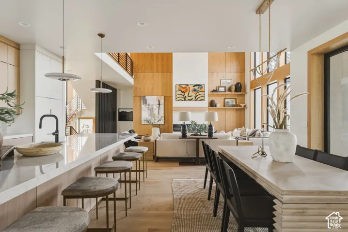 Expansive open-concept living space featuring wood-panel accent walls, high ceilings, and wood-finish flooring