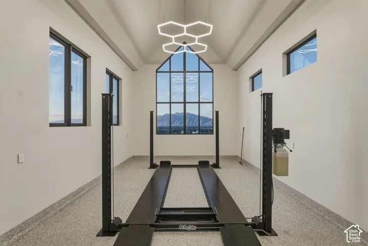 Automotive lift system within a spacious garage featuring a vaulted ceiling and an expansive multi-pane window framing a mountain backdrop