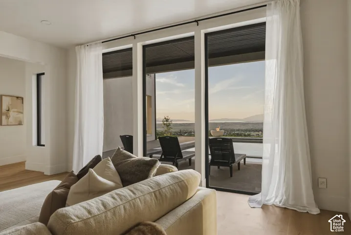 Expansive glass sliding doors with sheer drapery open to an outdoor patio with distant scenery