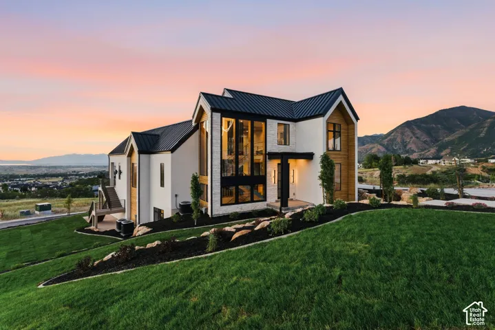Contemporary architectural design featuring a prominent black metal roof, white stucco, and wood-finish siding accents