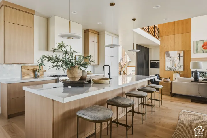 Open-concept kitchen featuring an oversized island with seating, integrated sink, and contemporary pendant lighting