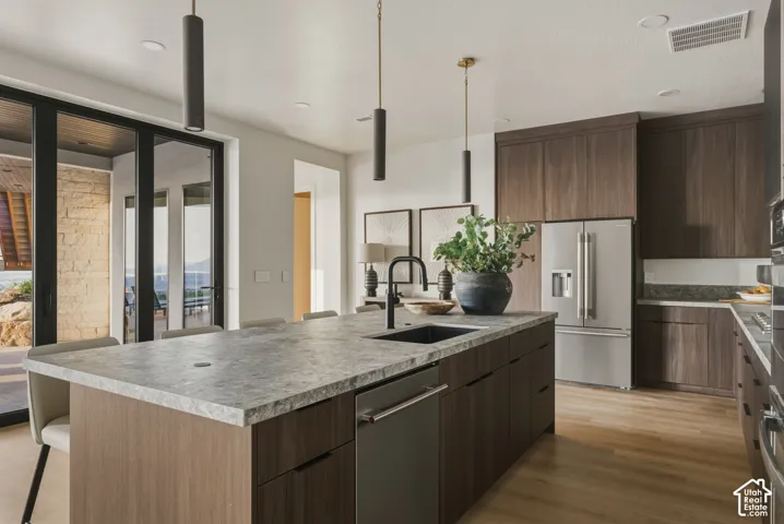 Kitchen island featuring a dark stone-finish countertop, undermount sink, and integrated dishwasher