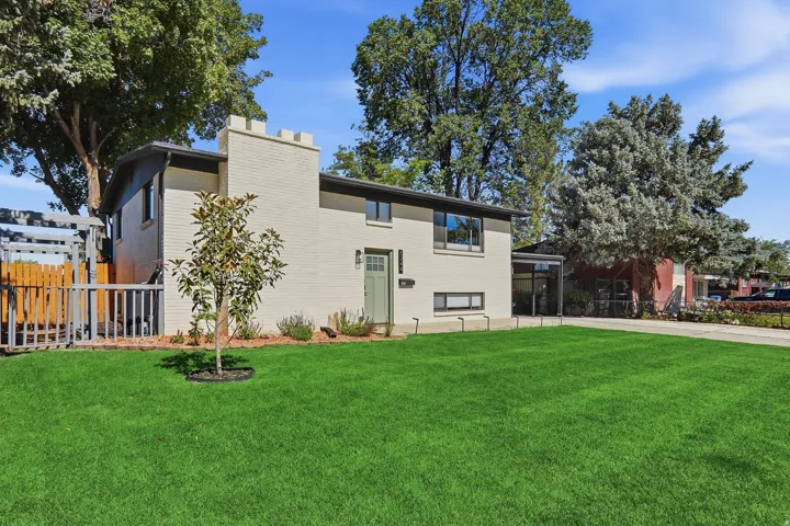 Split-level residence featuring a light-colored brick exterior, a castle-style chimney, and a mint green entry door
