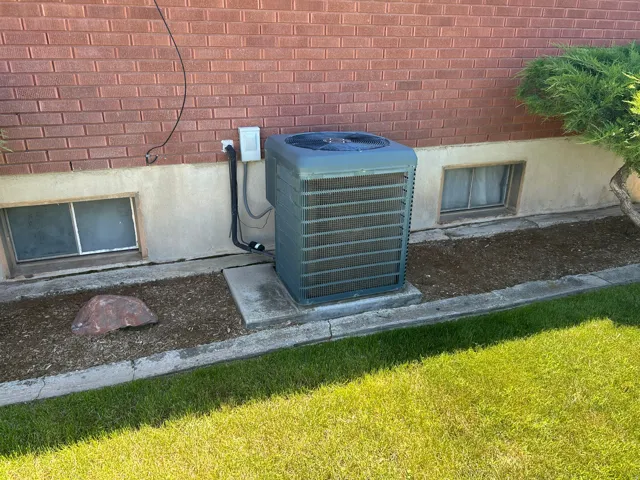 Brick veneer exterior with a foundational stucco band, featuring a central HVAC unit on a concrete pad